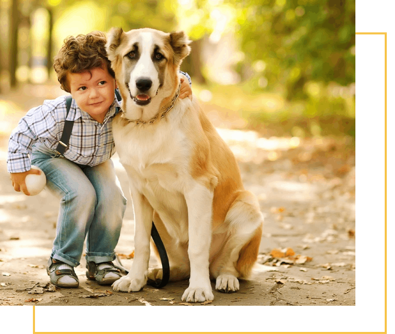 A boy and his dog are sitting on the ground.