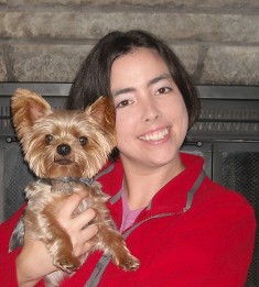 A woman holding her dog in front of a fireplace.